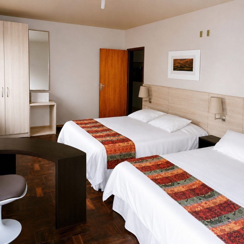 Quarto da Pousada São José com duas camas de casal e roupa de cama branca